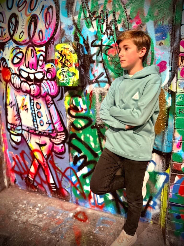 Boy wearing The Decried green mini hoodie leaning against wall