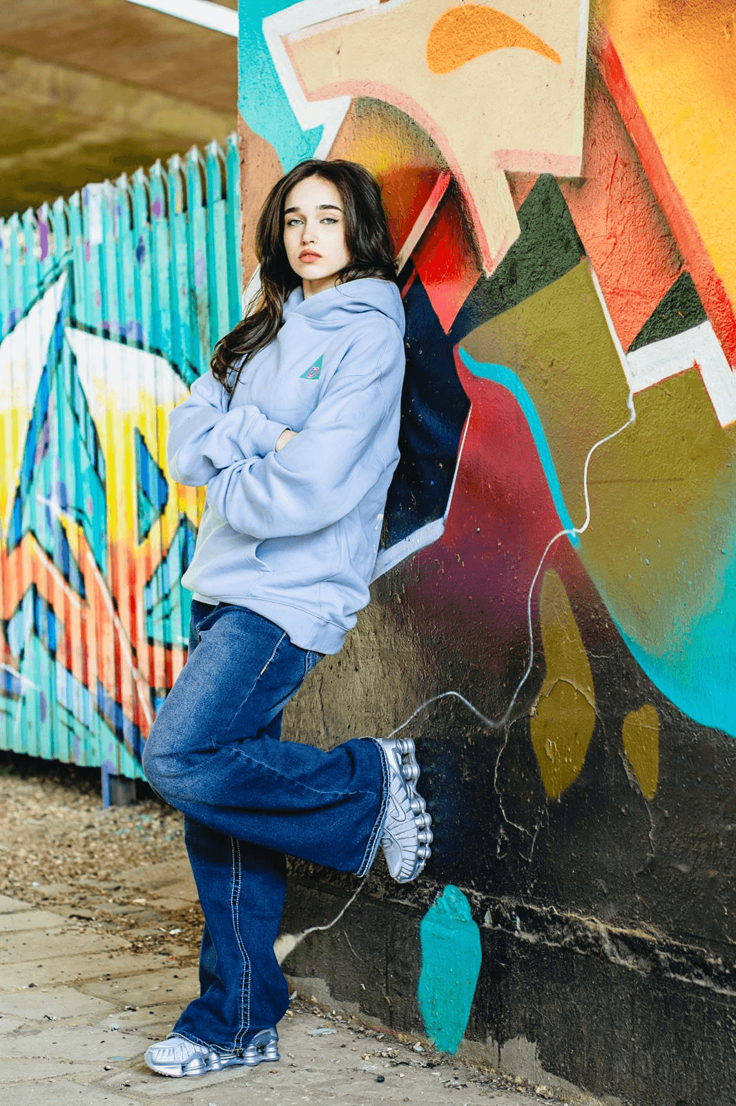 Woman wering The Decried blue hoodie leabing on wall