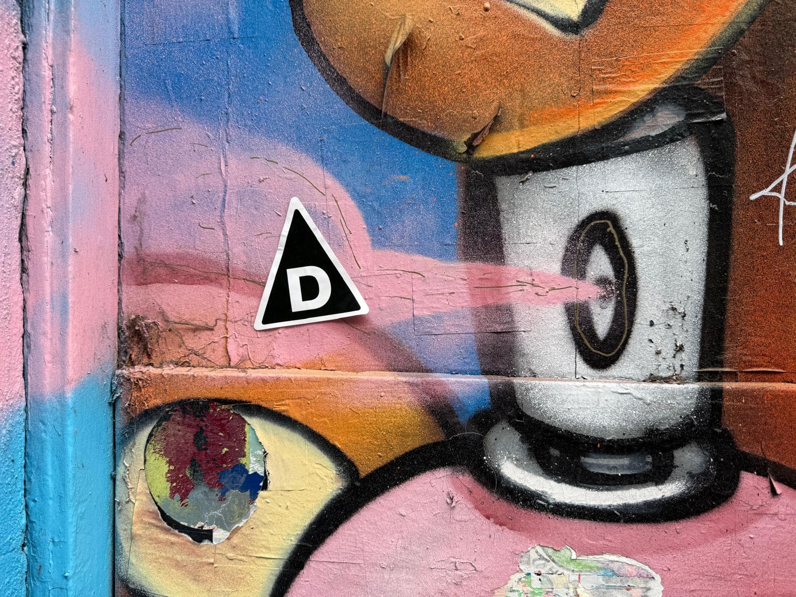 Colourful grafitti wall with The Decried logo sticker